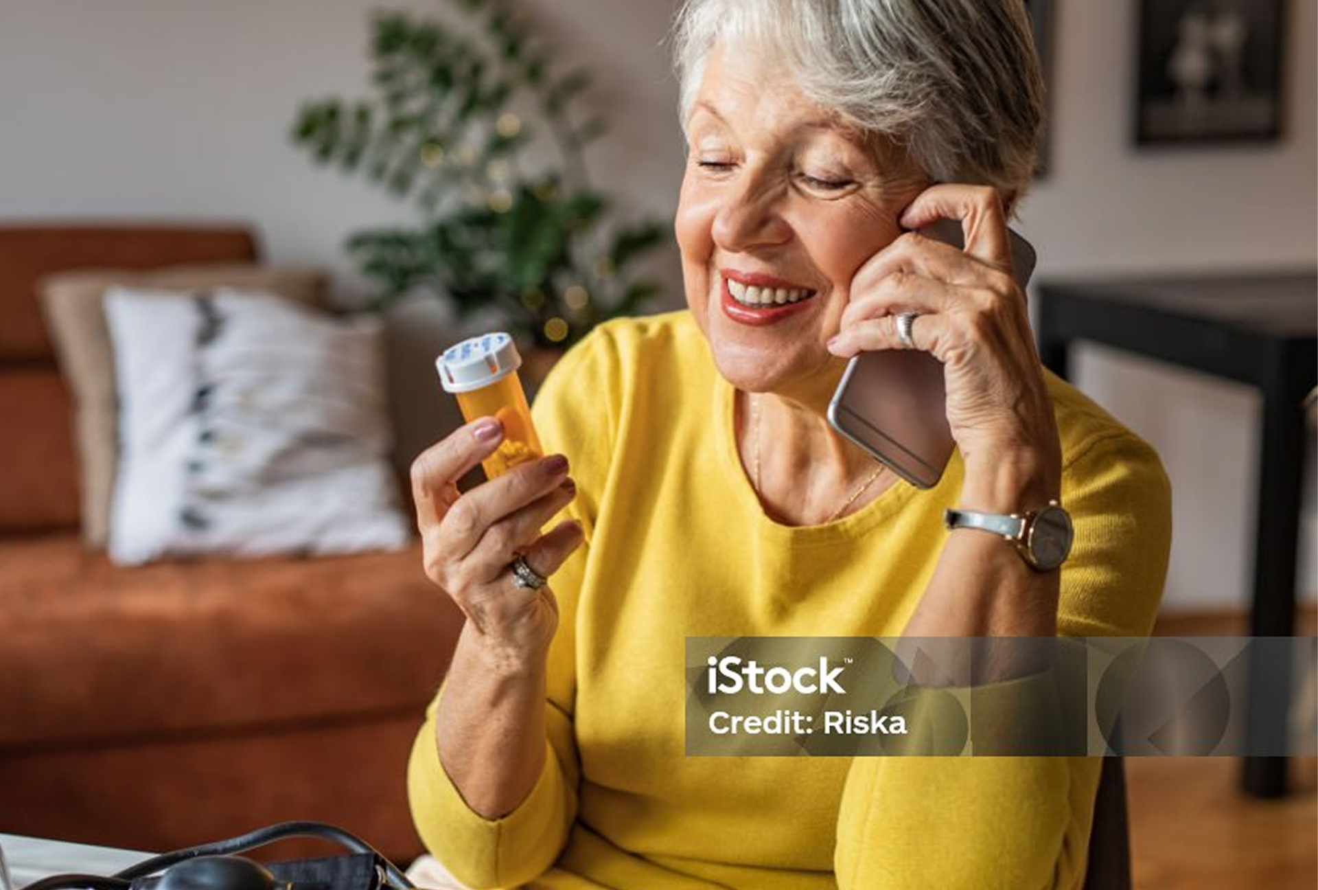 Older woman on the phone reads from the label of a prescription bottle